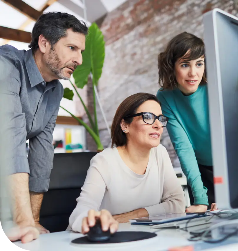 A lending team works collaboratively on a desktop computer in an office setting