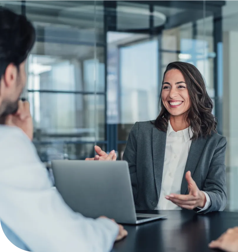 A smiling woman converses with a male colleague in an office setting