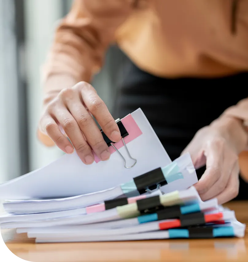 A woman flips through a stack of paper documents