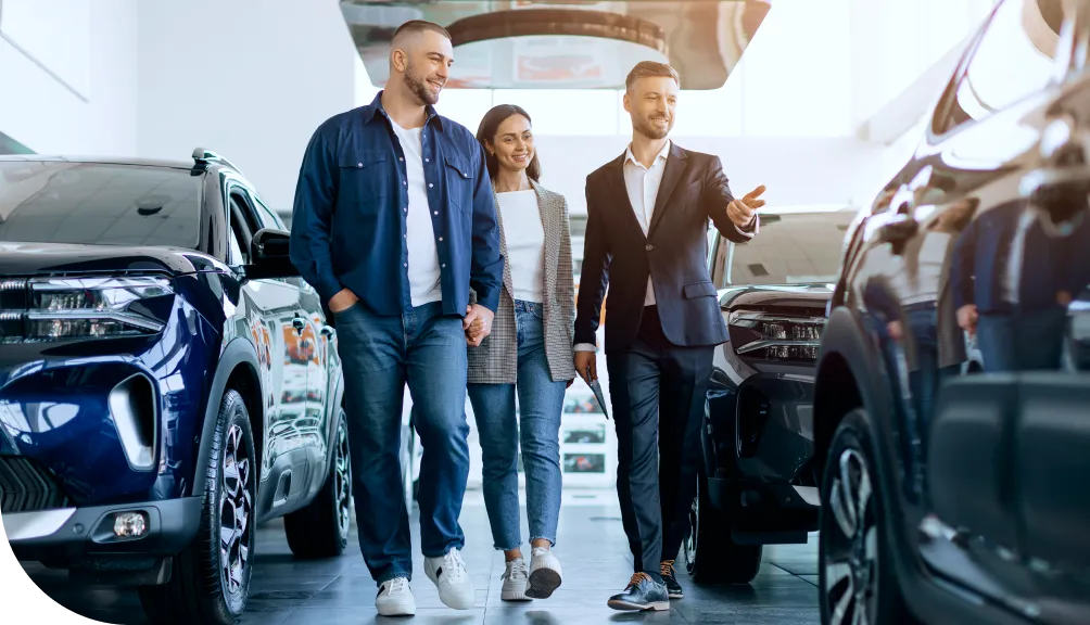 A couple walk through a dealership showroom with a salesman
