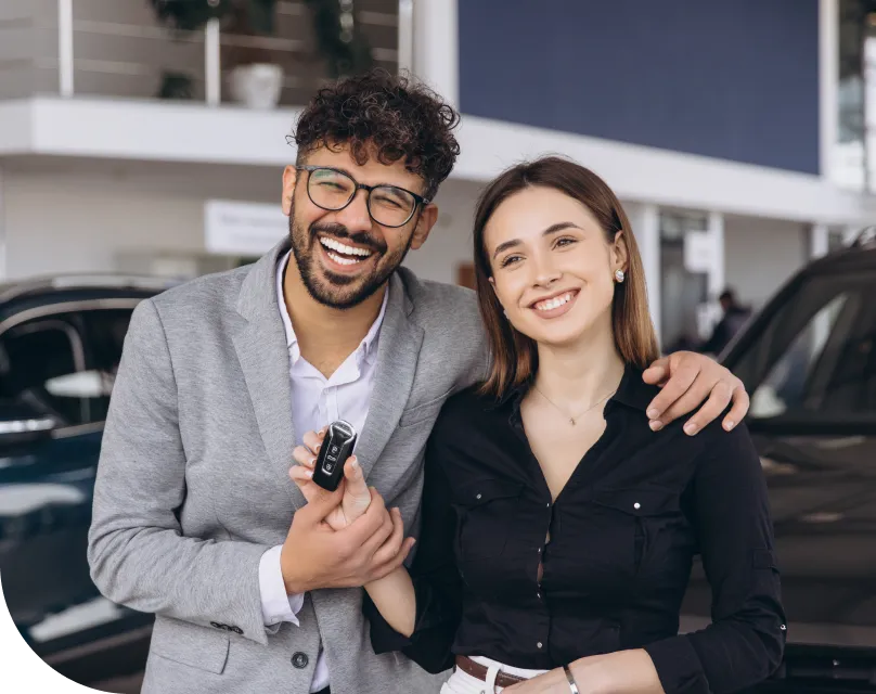 A woman receives the keys to her new car at the dealership
