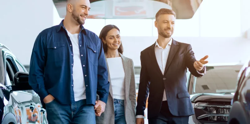 A couple walk through a dealership showroom with a salesman