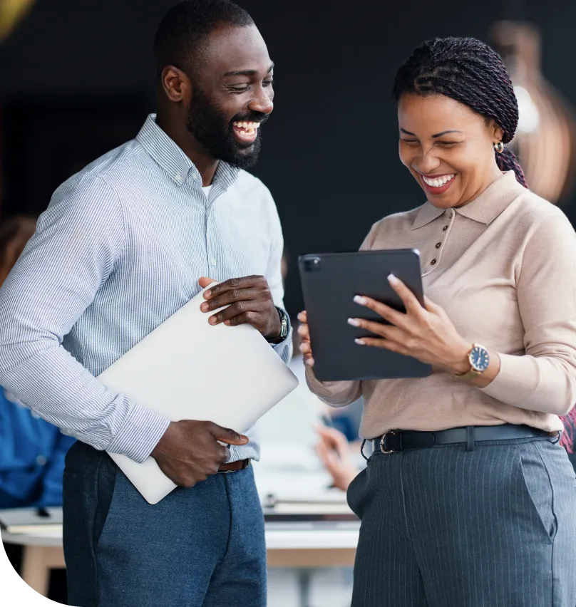 Two co-workers smiling as they view a tablet computer