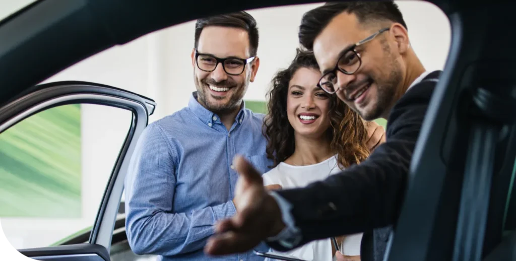 A salesman shows a couple the interior of a car