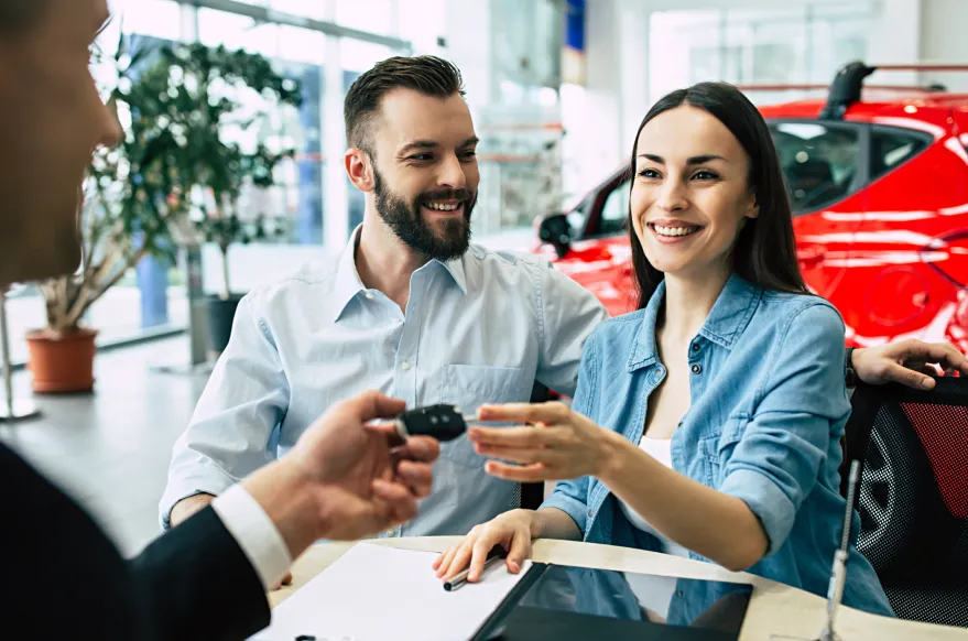A couple receive the keys to their newly purchased car at a dealership