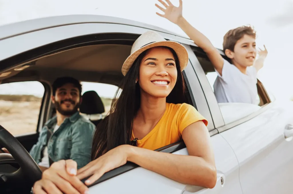 A happy family sits inside their car