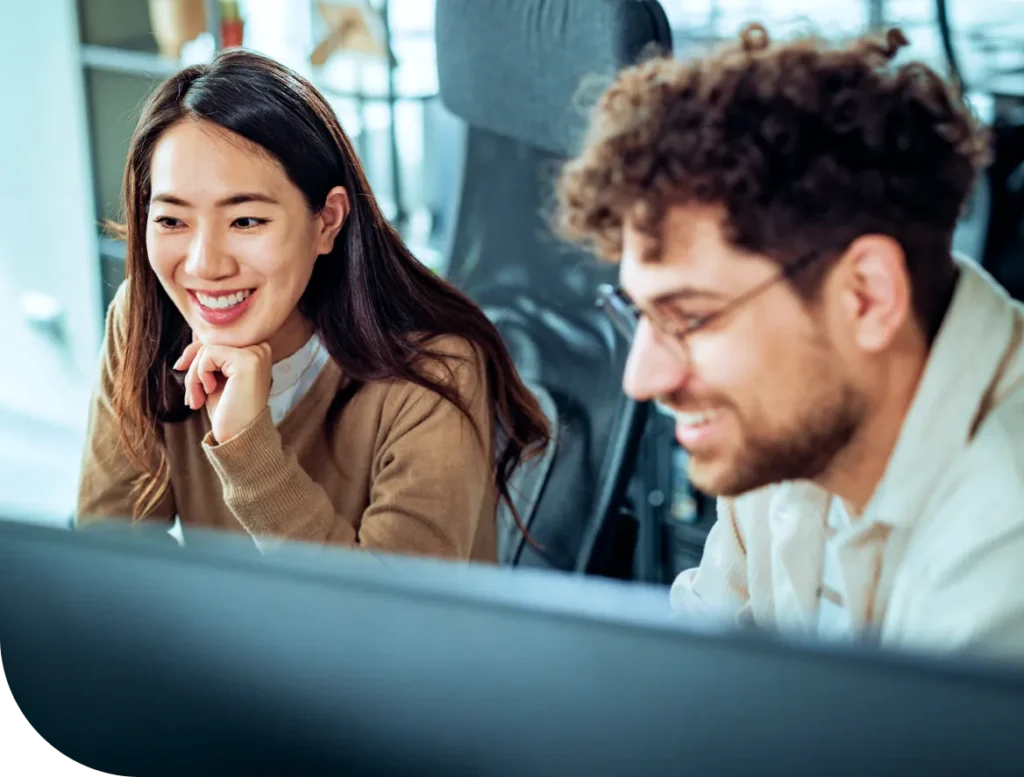 A man and woman collaborate on a computer in an office