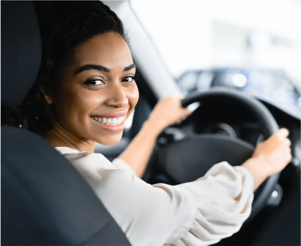 A smiling woman in the driver seat of a car