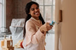 A woman paints a room inside a home.
