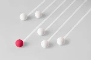 White colored spheres at various positions and a magenta colored sphere ahead of them representative of credit union portfolio diversification.