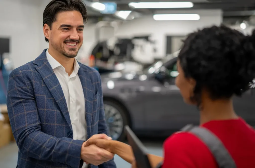 Salesperson shaking hands with a new customer representing auto lending success.